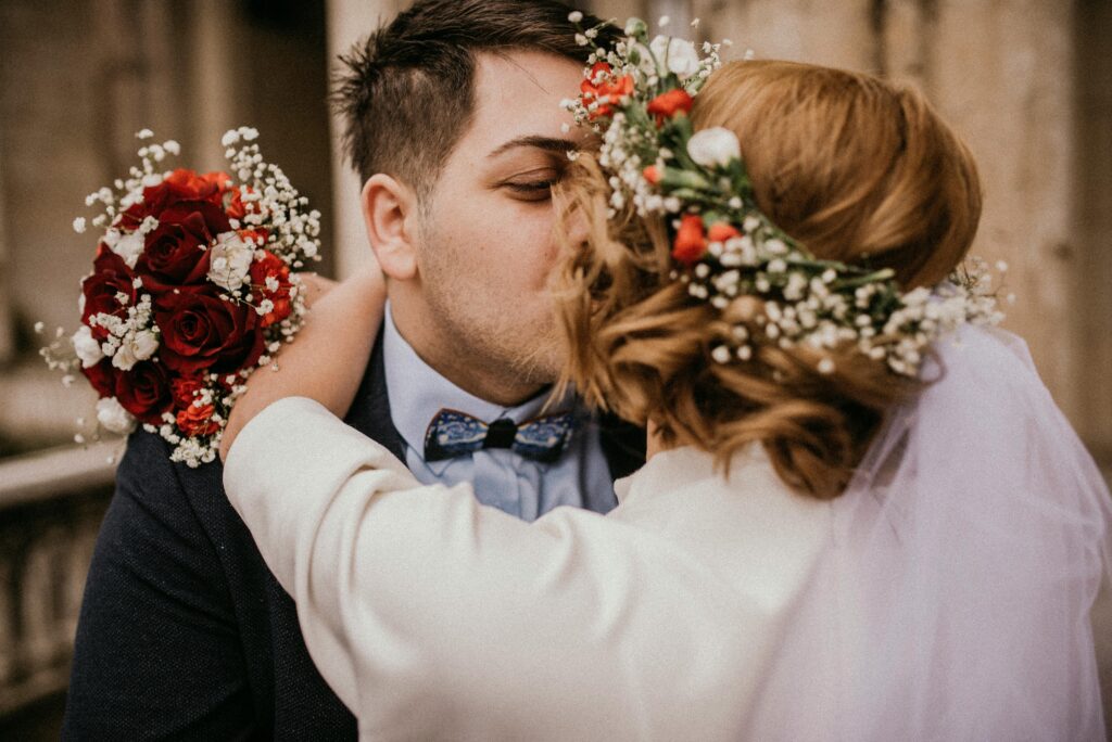 A bride and groom sharing a romantic kiss on their wedding day, symbolizing love and partnership.