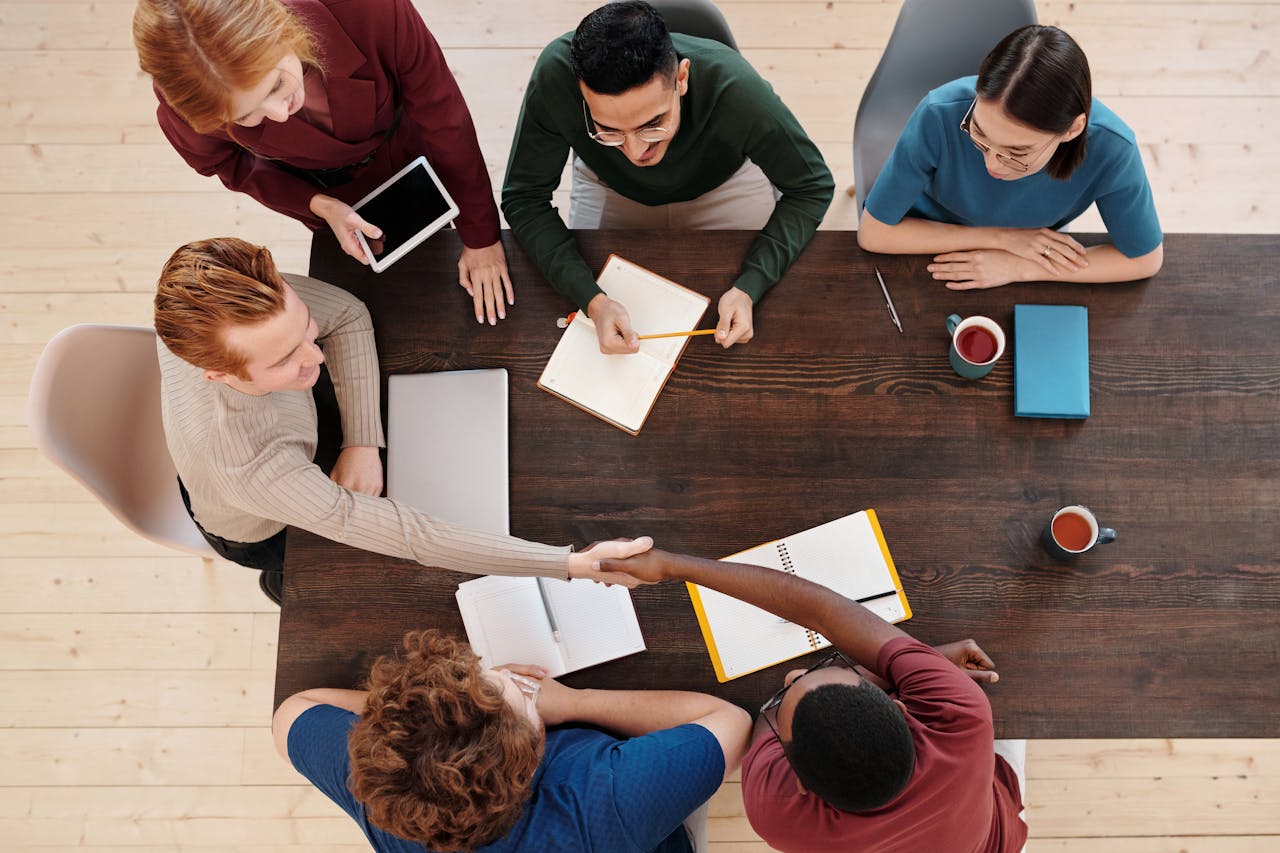 Top view of a diverse business team meeting with a handshake across the table. Collaborative working environment.